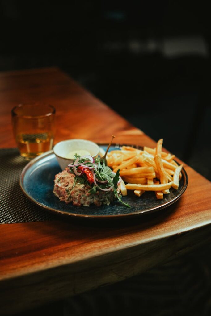 A mouthwatering steak tartare served with crispy french fries on a wooden table.