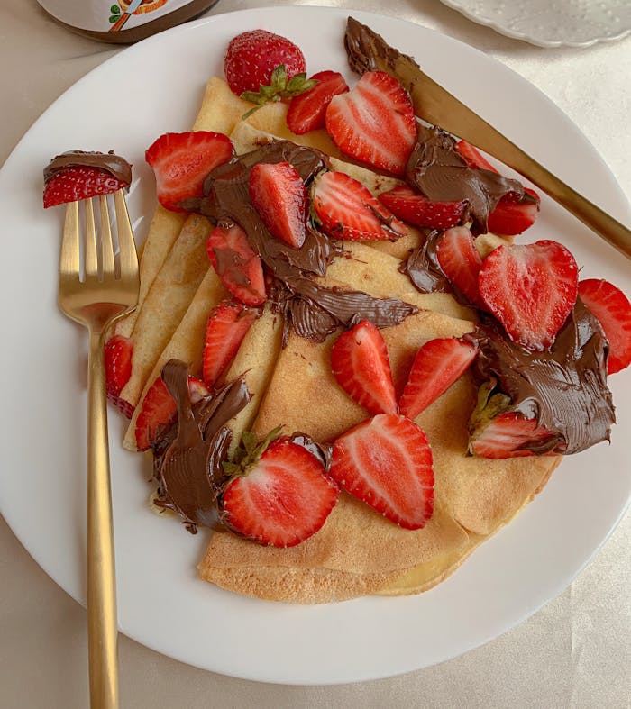 Mouthwatering crepes topped with fresh strawberries and luscious chocolate spread.